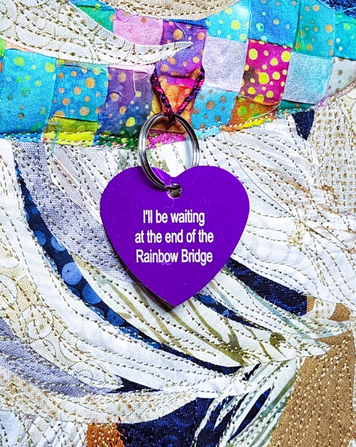 The back of the purple heart dog tag reading 'I'll be waiting at the end of the Rainbow Bridge'
