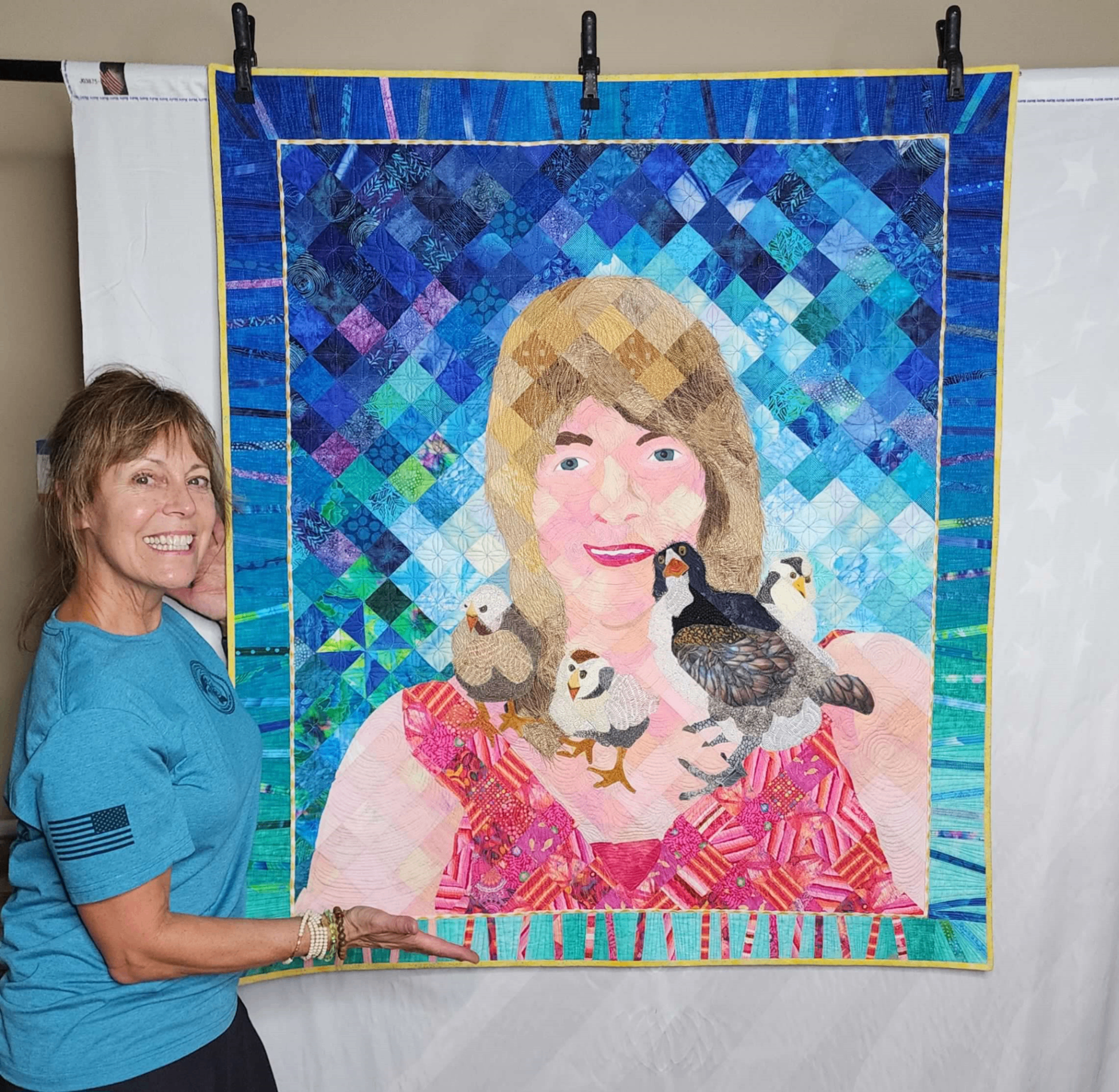Woman standing next to the quilt hanging on a wall